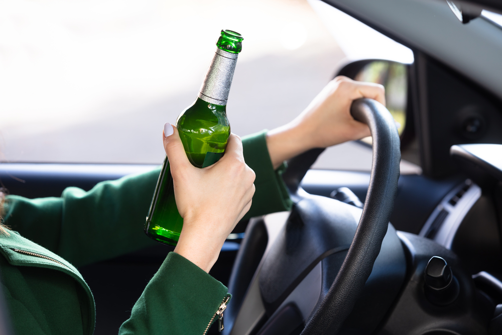 Tânără cu sticlă de alcool la volan/ Foto: depositphotos.com