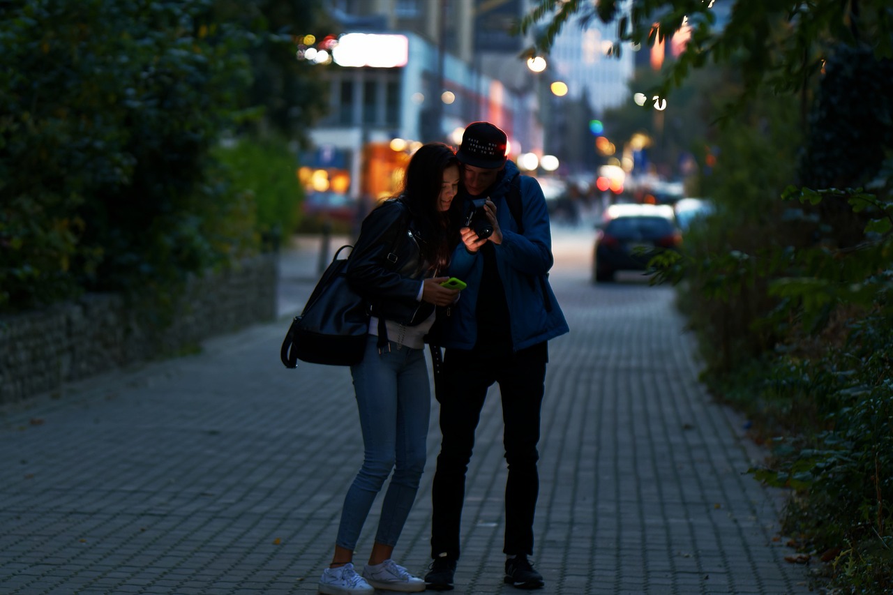 Tineri pe stradă care se uită într-un telefon mobil. Foto: Pixabay