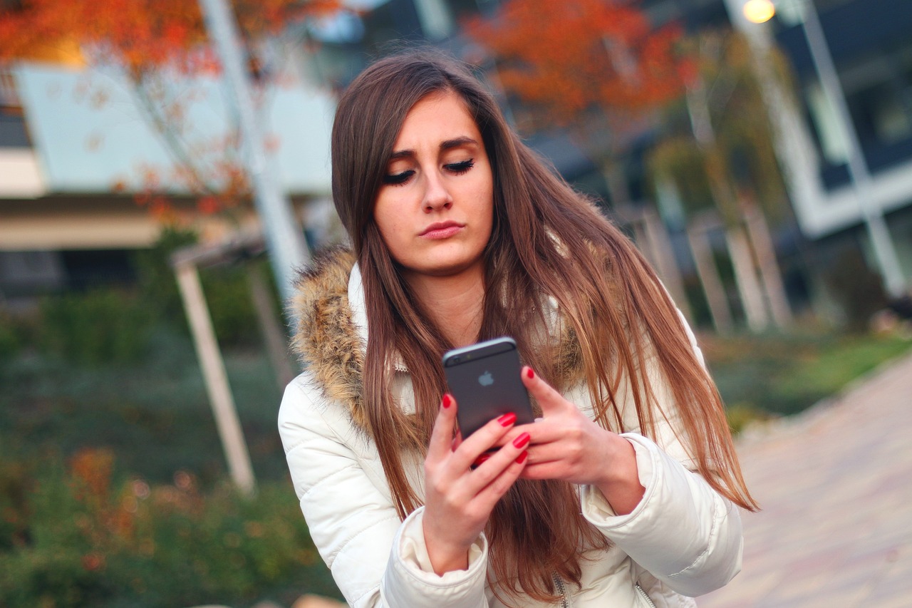 Tânără care ține în mână un telefon Apple. Foto: Pixabay