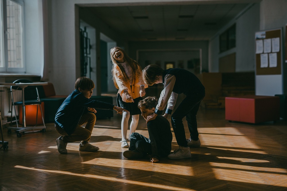 Trei copii batjocoresc și râd de un băiat în școală/ Foto: pexels.com