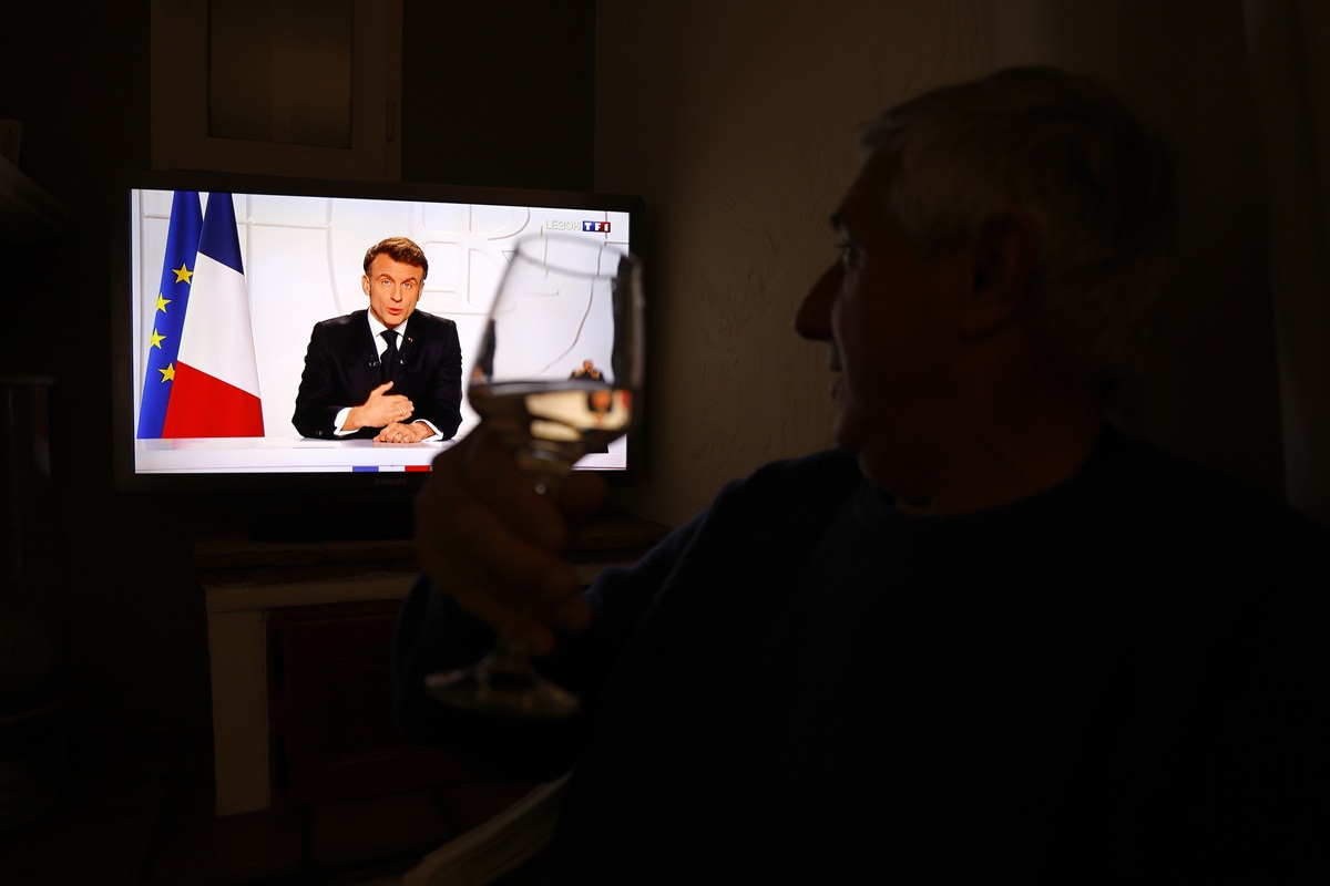 Un bărbat urmărește discursul televizat al președintelui Macron